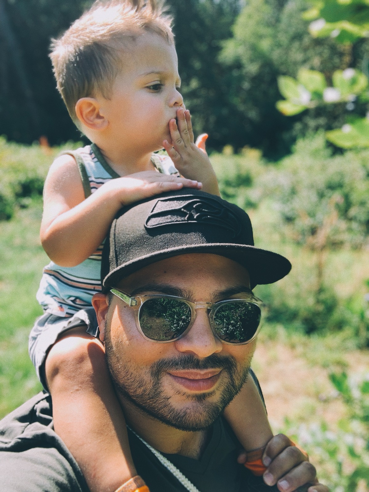 A toddler riding on my shoulders through a berry field